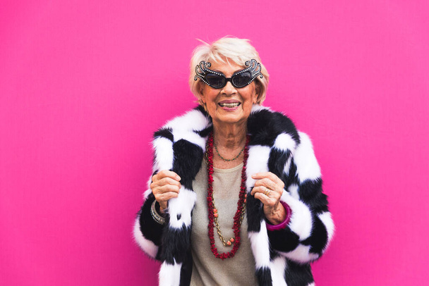 Happy and playful senior woman having fun - Portrait of a beautiful lady above 70 years old with stylish clothes, concepts about senior people - Фото, изображение