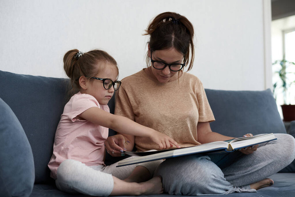 Matka i córka czytają książkę. Matka uczy małą dziewczynkę.. - Zdjęcie, obraz
