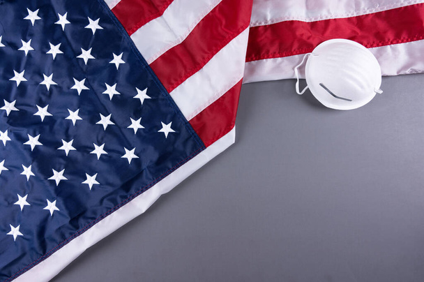 Amerikaanse vlag met gezichtsmasker op een donkere achtergrond, tijdens een pandemie. 4 juli, Dag van de Veteranen, Dag van de Vlag, 14 juni, Dag van de Arbeid, herdenkingsdag, Vakantie concept. - Foto, afbeelding