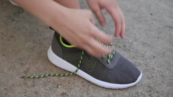 Ayakkabı bağcıklarını koşu ayakkabılarına bağlayan kıza yakın dur. Spor ayakkabılarına ayakkabı bağlayan kadın elleri antrenman yapıyor.. - Video, Çekim