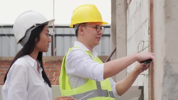 Hombre y mujer en sombreros discutiendo el proceso de trabajo en el sitio de construcción - Metraje, vídeo