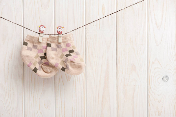 new baby socks hanging on clothesline over wood background, newborn and baby concept - Photo, Image