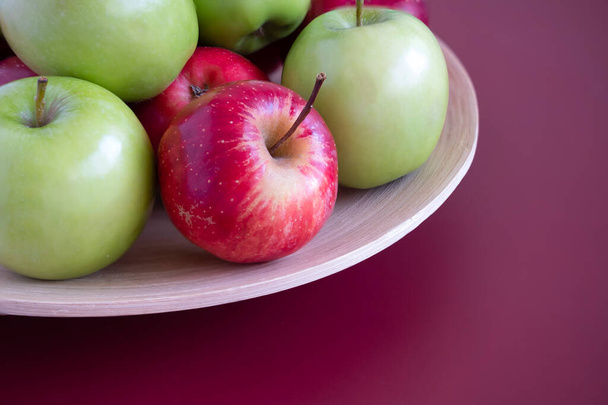 Close-up van rode en groene appels op een bamboeplaat. Mahonie achtergrond. - Foto, afbeelding