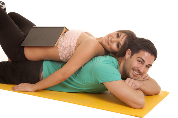Woman lay on mans back book on her stomach - Фото, изображение