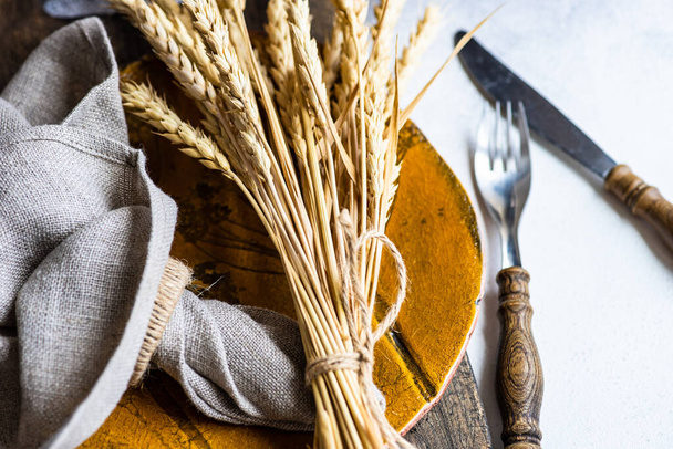 Rustic table setting with cutlery decorated with whear ears on concrete background with copy space - 写真・画像