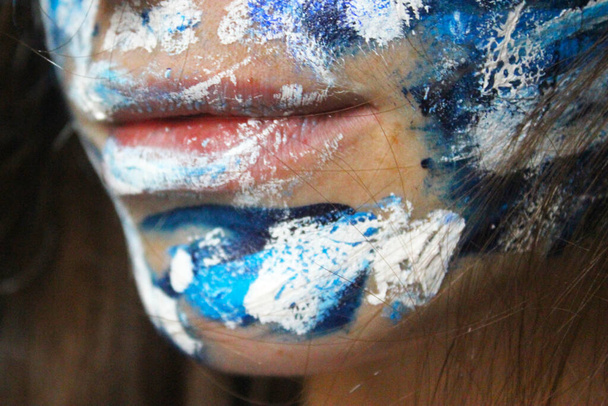 Geschilderd gezicht met acryl blauw en witte kleuren. jong mooi vrouw portret, close-up foto. - Foto, afbeelding