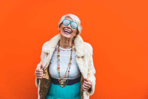 Happy and playful senior woman having fun - Portrait of a beautiful lady above 70 years old with stylish clothes, concepts about senior people - Фото, изображение
