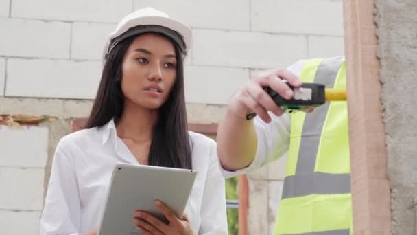 Muž a žena v klobouku diskutovat o pracovním procesu na staveništi - Záběry, video