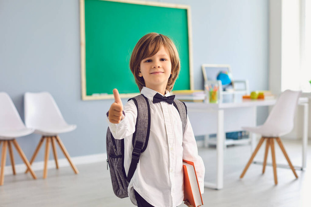Back to school.Happy schoolboy with backpack smiling raised his thumb upstairs in class. - Foto, Imagem