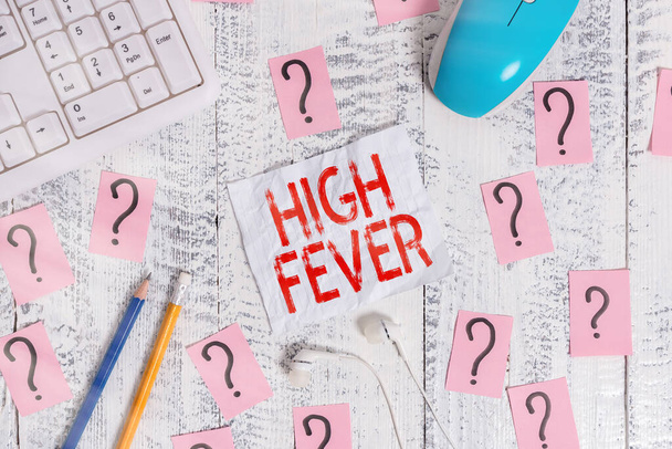 Text sign showing High Fever. Conceptual photo medical condition which the body temperature higher than usual Writing tools, computer stuff and scribbled paper on top of wooden table. - Photo, Image