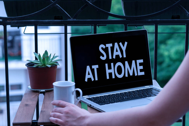 Text sign showing Stay At Home. Conceptual photo movement control restricting individuals from getting exposed publicly Personal workplace overview with laptop device used for individual interest. - Photo, Image