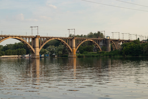 most kolejowy przez rzekę Dniepr w mieście Dniepr o zachodzie słońca - Zdjęcie, obraz