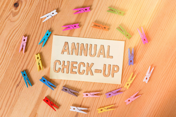 Text sign showing Annual Checkup. Conceptual photo yearly reproductive health visit with a health care provider Colored clothespin papers empty reminder wooden floor background office. - Photo, Image