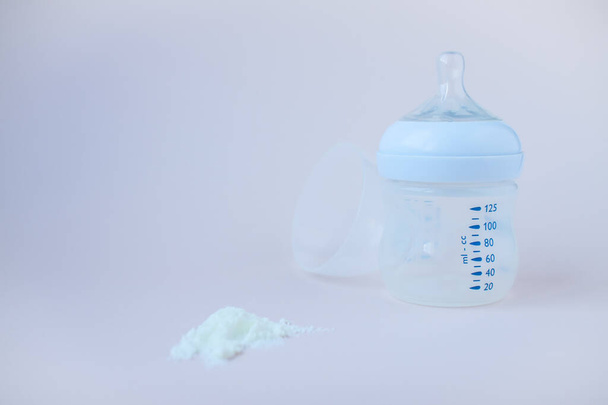 Artificial feeding of babies. Bottle for the mixture, measuring spoon, dry milk adapted mixture. Silicone rodent in pastel colors. Copy space for text. - Fotografie, Obrázek