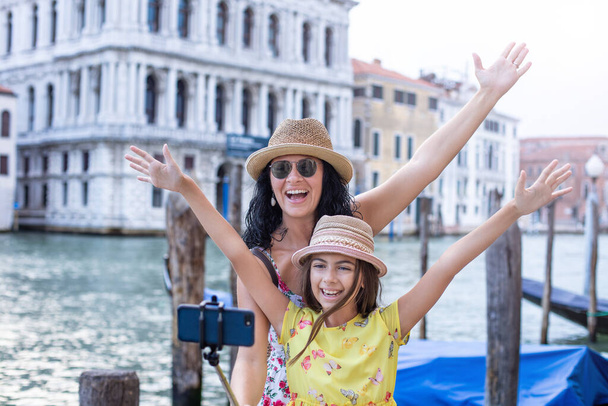 Uma mãe está tirando selfie com sua filha em Veneza. Conceito de fotografia com vara selfie
.  - Foto, Imagem