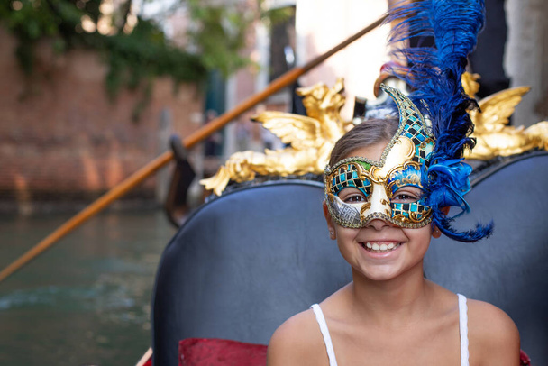 女の子はイタリアのヴェネツィアでゴンドラで楽しんでいます。ベネチアンマスクと家族のコンセプト. - 写真・画像