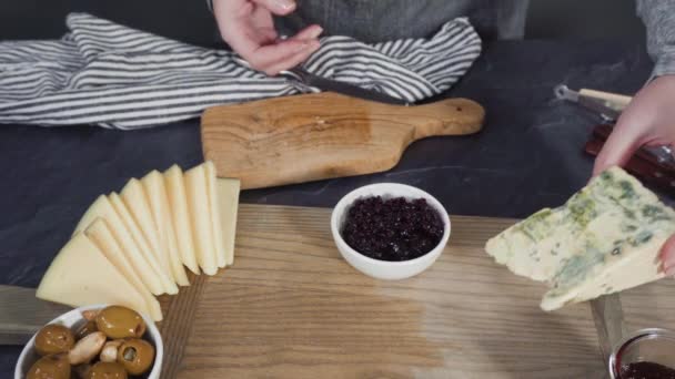 Az ínyenc sajtok, kekszek és gyümölcsök elrendezése egy táblán egy nagy sajttáblához. - Felvétel, videó