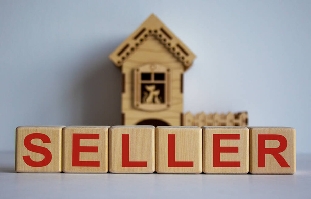 Cubes form the word 'seller' in front of a miniature house. Beautiful white background. - Fotografie, Obrázek