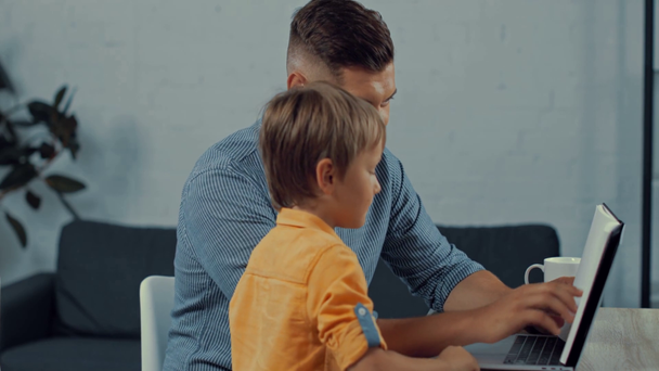 słodkie chłopiec wprowadzenie notatnik na laptop szczęśliwy ojciec w domu - Materiał filmowy, wideo