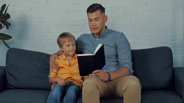 guapo padre leyendo libro en voz alta a lindo hijo en casa
 - Imágenes, Vídeo
