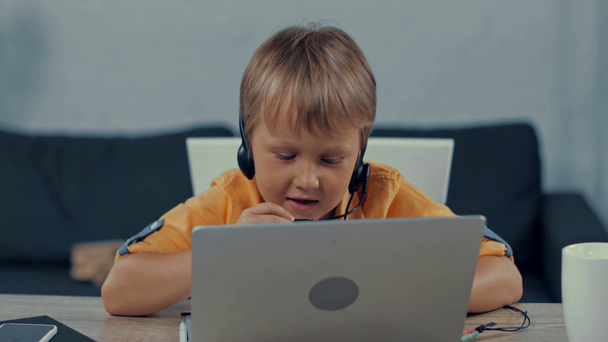 selektivní zaměření chlapce ve sluchátkách mluvení při hraní a používání notebooku  - Záběry, video