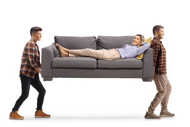 Woman laying on a sofa carried by two young men isolated on white background - 写真・画像