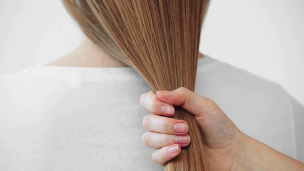 Weibliche Hand berührt Haare der jungen Frau isoliert auf grau - Filmmaterial, Video