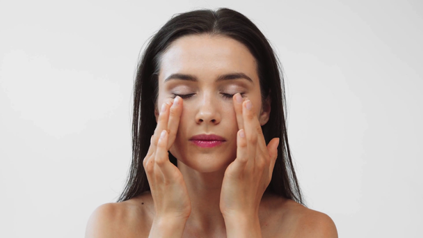 piękna naga kobieta robi masaż twarzy odizolowany na szary - Materiał filmowy, wideo
