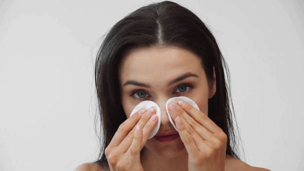 Hermosa chica desnuda limpiando la cara con almohadillas de algodón y sonriendo aislado en gris
 - Metraje, vídeo