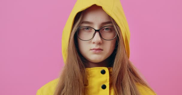 Serious girl in yellow raincoat looking at camera - Πλάνα, βίντεο