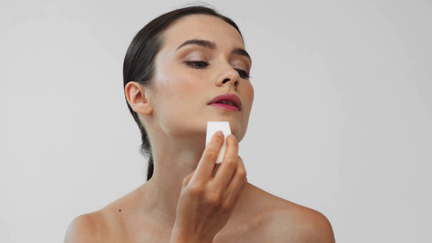 Mooie naakte vrouw met make-up spons geïsoleerd op grijs - Video