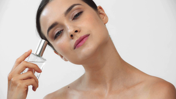 Beautiful naked woman holding bottle of perfume on grey background - Metraje, vídeo