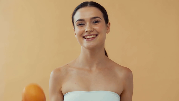 Hermosa mujer sonriente lanzando pomelo aislado en beige
 - Metraje, vídeo