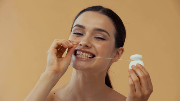 Hermosa mujer usando hilo dental aislado en beige
 - Metraje, vídeo