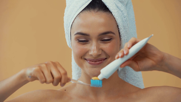 Dívka s ručníkem na hlavě drží zubní kartáček a zubní pastu izolované na béžové - Záběry, video