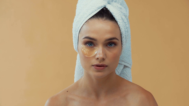 Schöne Mädchen mit Handtuch auf dem Kopf Anwendung Kollagen-Pads isoliert auf beige - Filmmaterial, Video