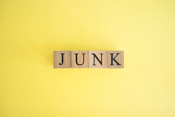 The word junk made of wooden cubes. The background is yellow and photographed in the studio. - Photo, Image
