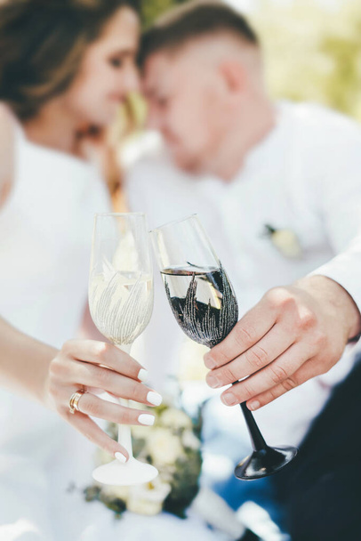 Nahaufnahme eines Glases mit einem schwarz-weißen Rand in den Händen an einem Hochzeitstag. - Foto, Bild