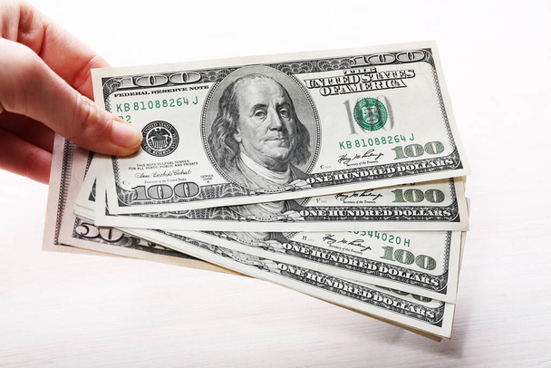 Billetes de dólares en mano sobre fondo claro, primer plano
 - Foto, imagen