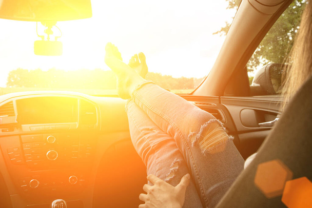 Kocsival. Szórakoztató vezető lovagolni jármű közúti utazás közben. Boldog fiatal nő belül autó naplementekor nyári nyaralás koncepció - Fotó, kép