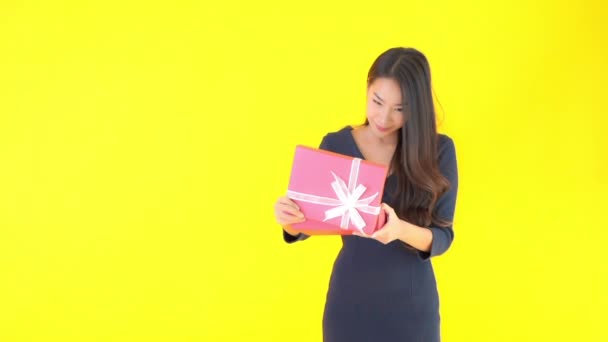 close-up footage of beautiful young Asian woman with pink gift box isolated on yellow - Video, Çekim