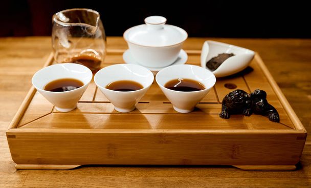 Traditionelles chinesisches Teetablett mit Drachen auf Tablett und gefüllten Wasserkochern  - Foto, Bild