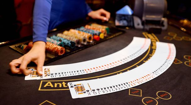 крутіший на покерному столі з коричневою тканиною відкладає карткові чіпси між руками
 - Фото, зображення