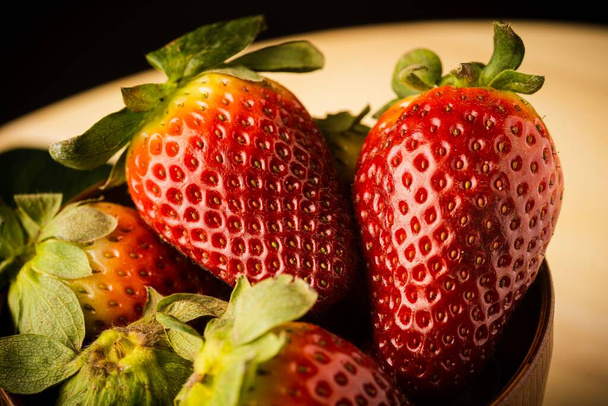 Fresh strawberries served on a wooden bowl, closed up, selective focus - Foto, Imagem