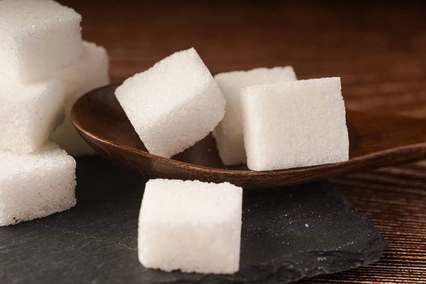 Zucchero cubetti con cucchiaio di legno. Concetto alimentare malsano - Foto, immagini
