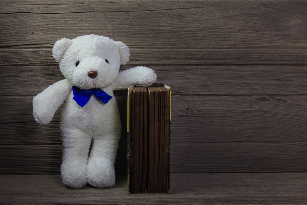 Ведмедик Тедді зі старою книгою на фоні дерева, натюрморт
 - Фото, зображення