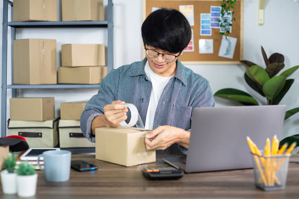 Asiatische Geschäftsmann Start-up KMU Unternehmer oder freiberuflich in einem Karton arbeitet bereitet Lieferbox für Kunden, Online-Verkauf, E-Commerce, Verpackung und Versandkonzept - Foto, Bild