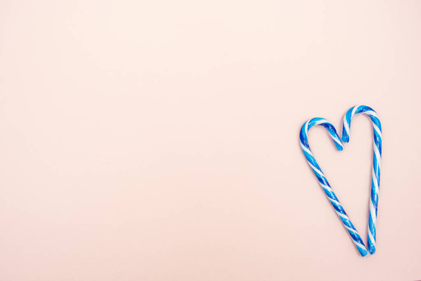 bastones de caramelo azul y blanco en forma de corazón sobre un fondo rosa, espacio de copia
 - Foto, imagen