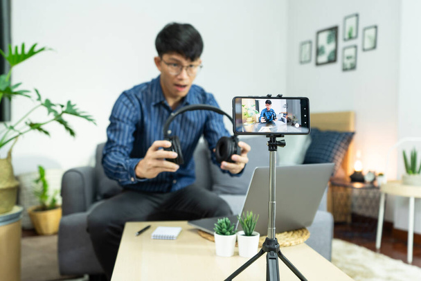 Asian man online influencer recording video live streaming, using digital smartphone camera present product review for theme about video blogging focus on camera screen show on social media - Photo, Image