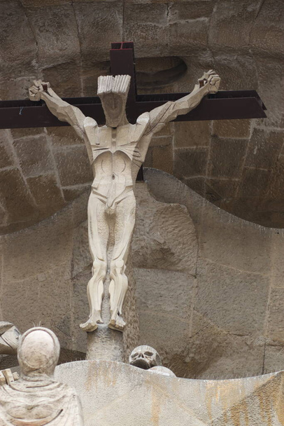 Una escultura que representa la crucifixión de Jesucristo frente a una catedral en España. Esta es una estatua moderna post piedra con bordes afilados
. - Foto, Imagen